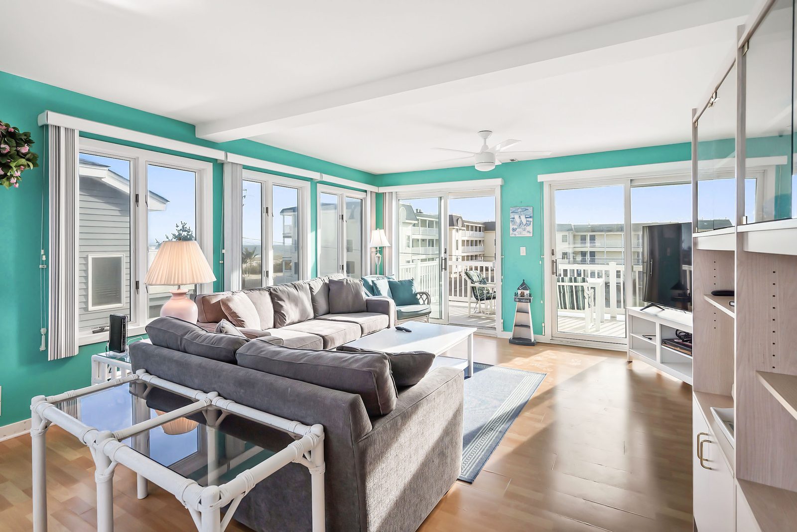 Turquoise top-floor living room with wraparound windows and deck access